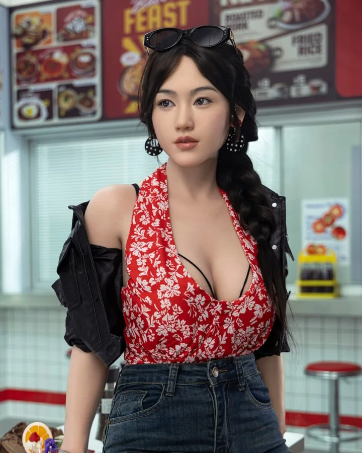 Asian doll with a long braid in a flower-print halter top, black jacket and jeans
