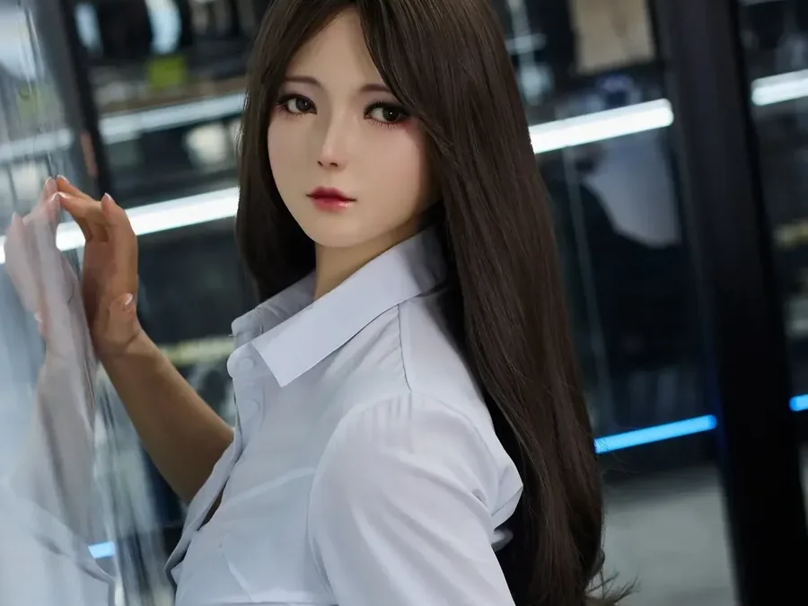 Doll with long dark hair in a white shirt by a glass wall